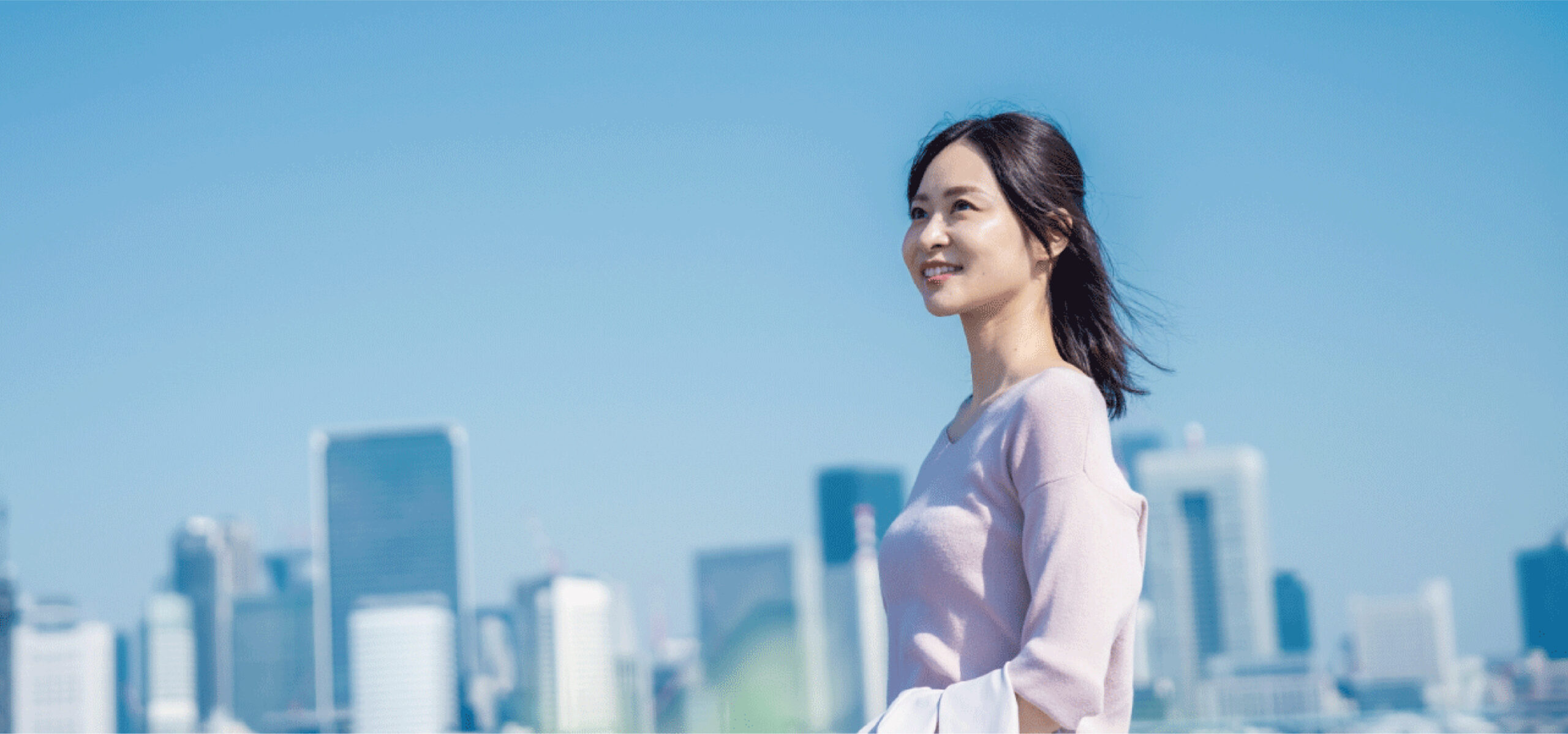 ビルをバックに空を見上げる女性